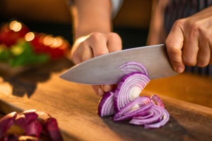 Pessoa cortando cebola roxa na cozinha