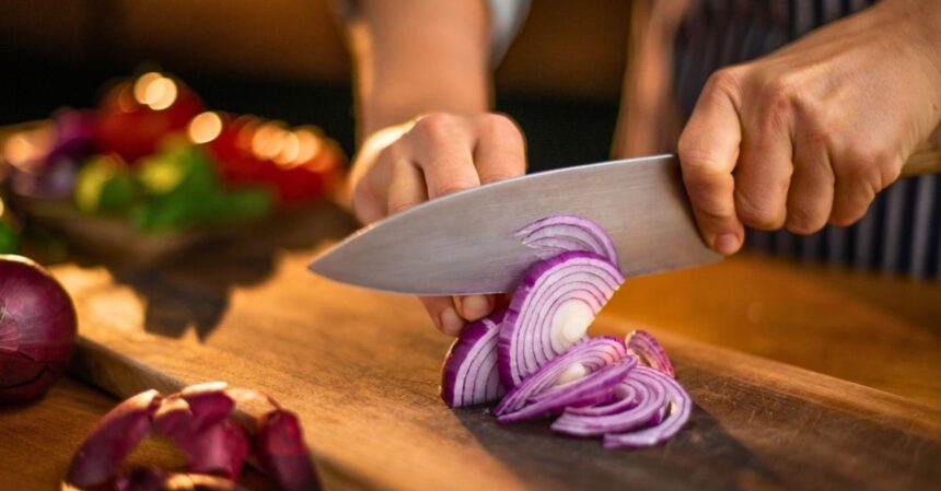 Pessoa cortando cebola roxa na cozinha