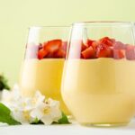 Imagem de uma sobremesa branca com morangos montada em um copo de vidro