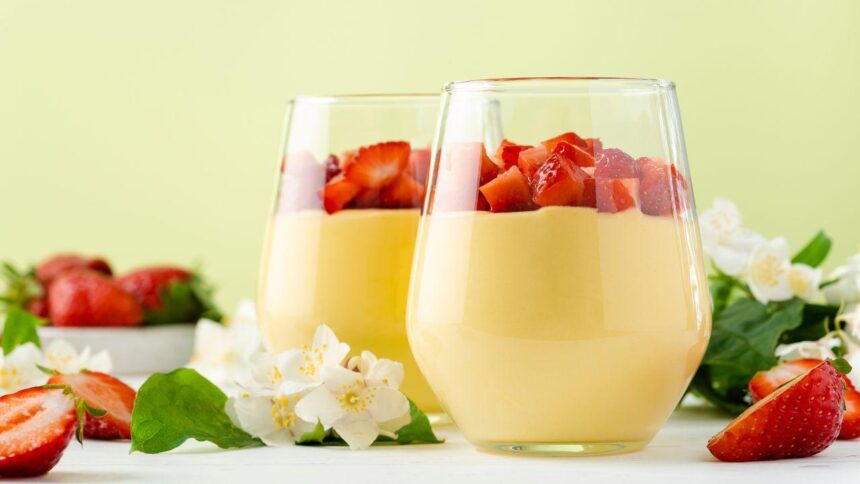 Imagem de uma sobremesa branca com morangos montada em um copo de vidro