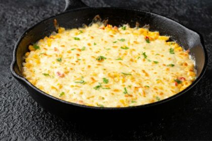 Foto mostra um omelete de legumes na frigideira em cima de uma bancada de mármore.