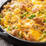 Prato com macarrão com queijo gratinado por cima numa bancada.