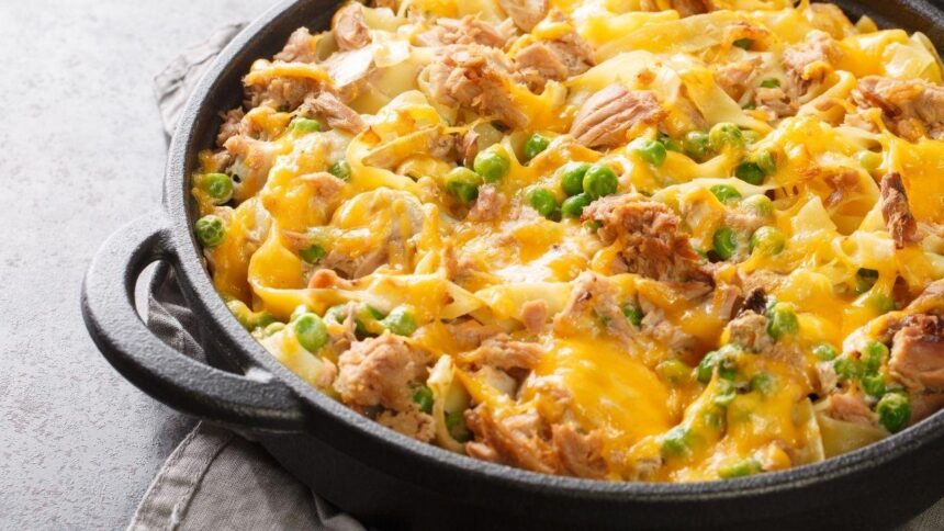 Prato com macarrão com queijo gratinado por cima numa bancada.