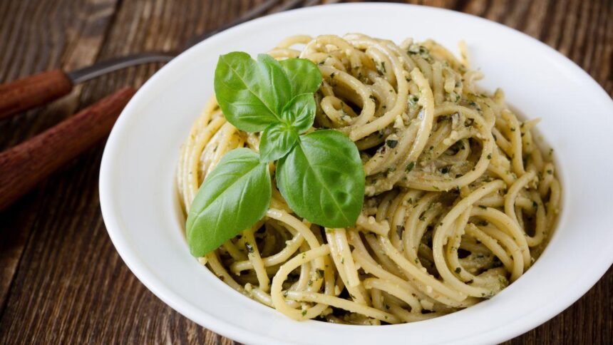 Foto mostra macarrão alho e óleo dentro de um prato branco em cima de uma mesa.