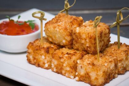 Dadinho de tapioca e um potinho de geleia de pimenta em cima de um prato.