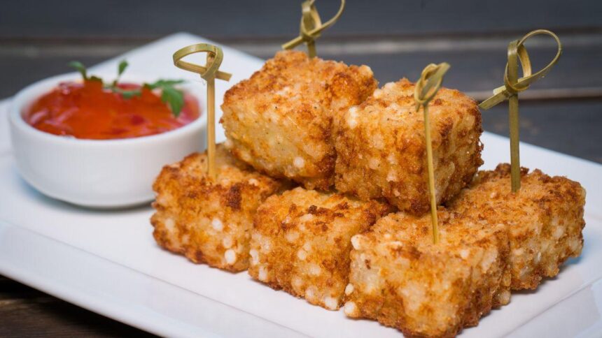 Dadinho de tapioca e um potinho de geleia de pimenta em cima de um prato.