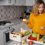 Mulher em cozinha organizada separando ingredientes e planejando o preparo do almoço para ganhar tempo no dia a dia.