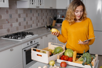 Mulher em cozinha organizada separando ingredientes e planejando o preparo do almoço para ganhar tempo no dia a dia.