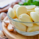 Imagem de dentes de alho descascados em um pequeno pote de vidro