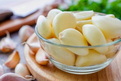 Imagem de dentes de alho descascados em um pequeno pote de vidro