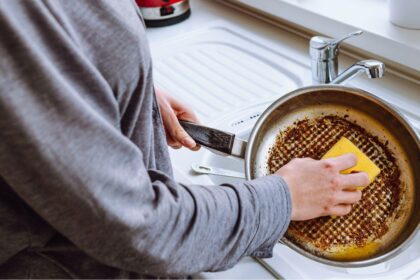 Foto de uma pessoa lavando uma frigideira com bastante resíduos