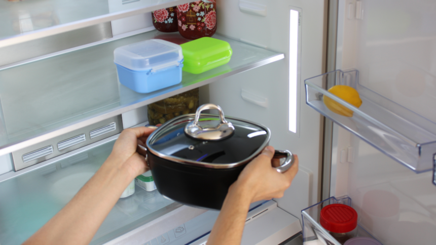 Imagem de uma pessoa colocando uma panela dentro da geladeira