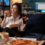 Imagem de uma mulher comendo comidas de delivery