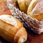 Pão francês dentro da cesta em cima de uma mesa.
