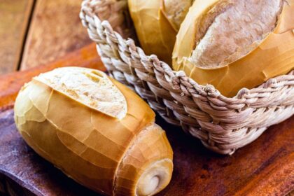 Pão francês dentro da cesta em cima de uma mesa.