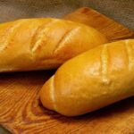 Imagem de dois pães franceses em cima de uma tábua de madeira