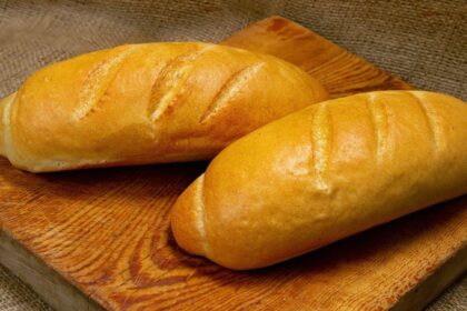 Imagem de dois pães franceses em cima de uma tábua de madeira