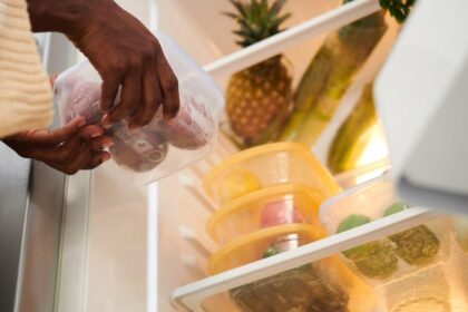Imagem de uma pessoa guardando comidas em potes na geladeira