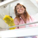 Imagem de uma mulher limpando a prateleira da geladeira