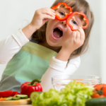 Imagem de criança brincando com alimentos na cozinha