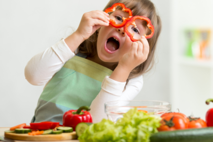 Imagem de criança brincando com alimentos na cozinha