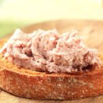 Mostra torradas com patê de atum em cima de uma mesa.