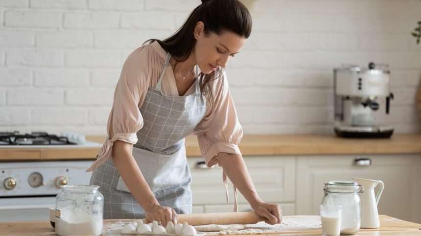 Mulher fazendo massa em cima da mesa.