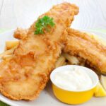 Filés de peixe frito dentro de um prato com pote de maionese ao lado.