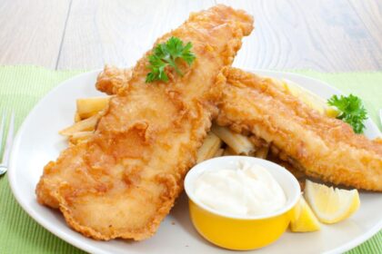 Filés de peixe frito dentro de um prato com pote de maionese ao lado.