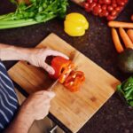 Imagem de um homem cortando pimentão vermelho