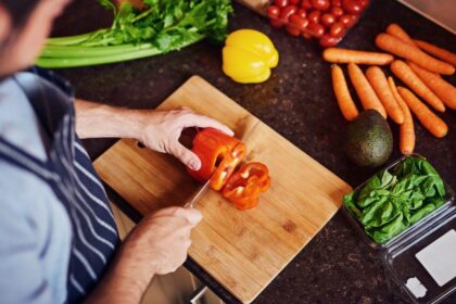 Imagem de um homem cortando pimentão vermelho