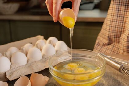 Imagem de uma pessoa quebrando ovos em um recipiente de vidro