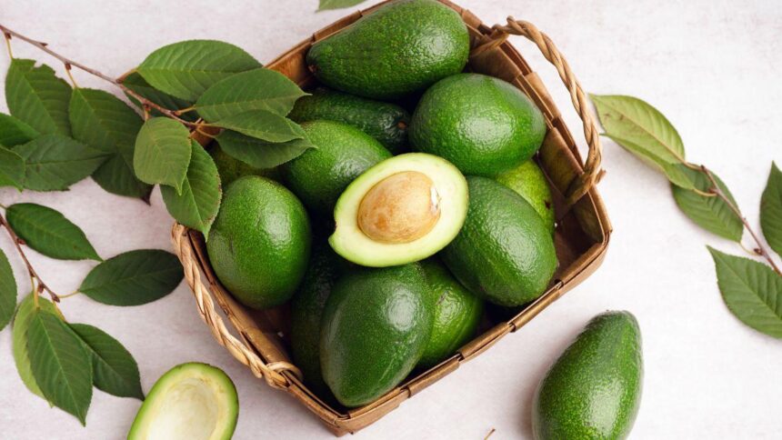 Foto mostra abacates dentro de uma cesta em cima da mesa.
