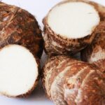 Foto mostra três inhames em cima de uma mesa cortados.