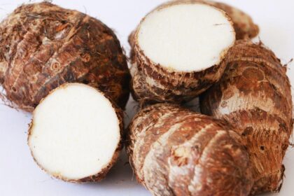 Foto mostra três inhames em cima de uma mesa cortados.