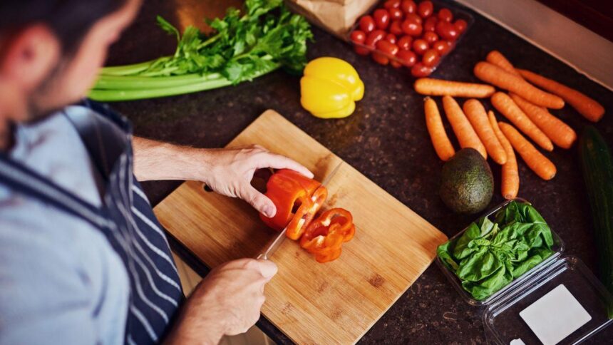 Homem cortando legumes em uma bancada.