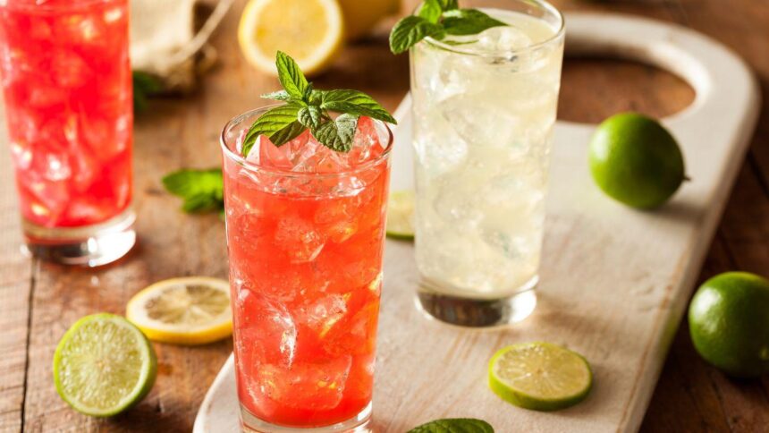 Foto mostra copos de drinks coloridos em cima de uma mesa.