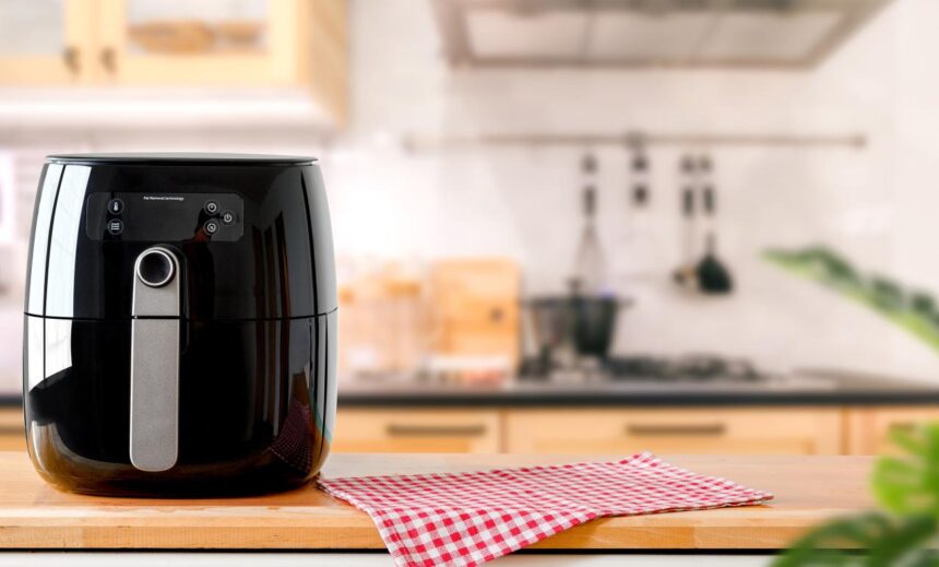 Foto mostra airfryer em cima de uma mesa na cozinha.