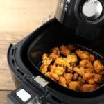 Air fryer aberta com frango frito dentro.