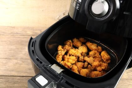 Air fryer aberta com frango frito dentro.