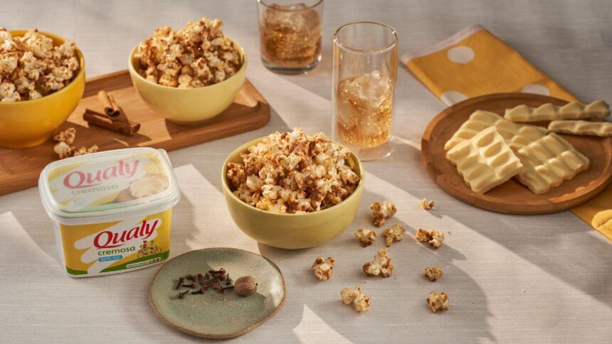 Imagem de pipocas em potes de cerâmicas em uma mesa, acompanhadas de copos de refrigerante com gelo e um pote grande de margarina Qualy