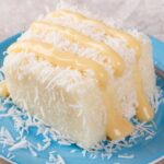 Imagem de uma fatia de bolo de coco com baba de moça por cima