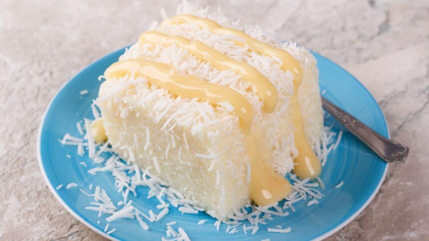 Imagem de uma fatia de bolo de coco com baba de moça por cima