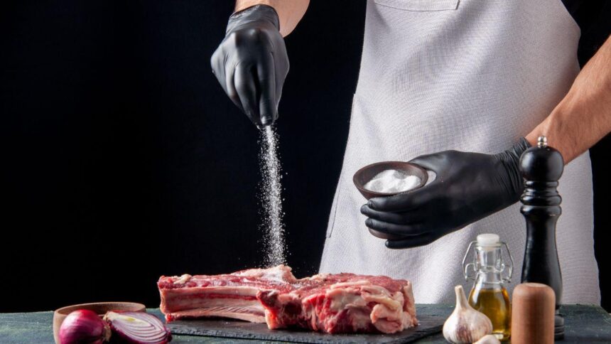 Pessoa temperando carne com sal