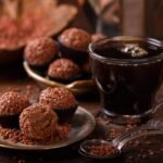A foto mostra brigadeiros enrolados dentro de um prato com uma xícara de café.