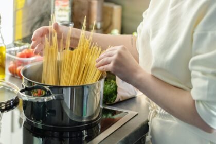 Mulher na cozinha preparando macarrão