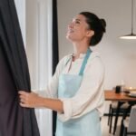 Imagem de uma mulher arrumando uma cortina longa