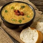 Imagem de um pote com sopa e fatias de pão ao lado