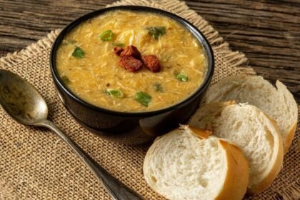 Imagem de um pote com sopa e fatias de pão ao lado