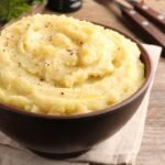 Imagem de uma porção de purê de batata em um pote marrom escuro